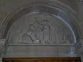  Carved stone tympanum showing mill workers at the loom with a sheet of finished cloth