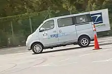  Small passenger van with alloy wheels driven at speed around a traffic cone