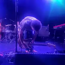 Ira Kaplan bent over a series of guitar pedals