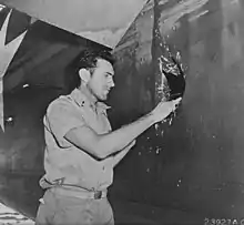 Image 91st Lt. Louis Zamperini, peers through a hole in his B-24D Liberator 'Super Man' made by a 20mm shell over Nauru, 20 April 1943. (from History of Tuvalu)