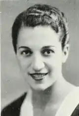 A photograph of a young smiling woman with short dark  glossy hair and dark eyes.