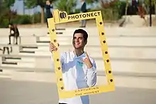 A smiling Ali, holding a frame