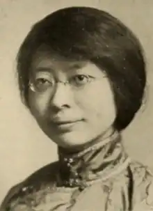 A young Chinese woman wearing eyeglasses and a high-collared silk blouse